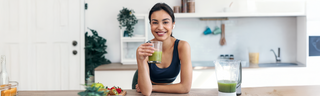 A young woman with brown hair enjoying a green smoothie with a collagen boost. 