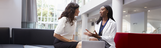 A woman consults with her surgeon in a sunny medical office as they discuss an upcoming procedure. 