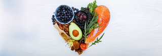 Heart-healthy foods arranged into the shape of a heart against a grey background