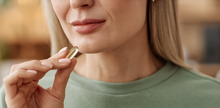 A blond woman in a green shirt takes her daily supplements.